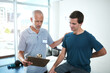 © peopleimages.com - Physiotherapist, man and back pain for consultation, health and wellness for sore muscle or fitness. Injury, male person and medical professional for appointment, clinic and rehabilitation center