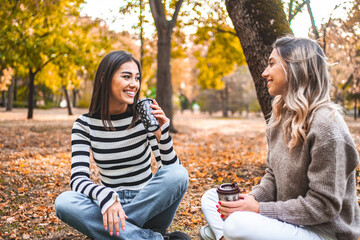 Two Women Sitting on the Ground Talking and Drinking Coffee