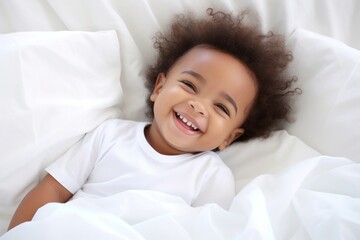 Poster - Smiling baby african girl lying on a bed sleeping on white sheets smiling smile comfortable.