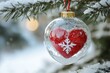 © Gatherina - Red christmas ornament heart hanging on a snowy pine tree branch