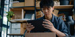 © Aigo labs - A young man sitting in an office and working on a tablet. He appears to be focused on his work. asian man
