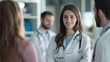 © jodoto - Female Doctor with Medical Team in Discussion - A friendly female doctor smiles confidently while engaging in a discussion with her medical team, showcasing a collaborative healthcare environment.