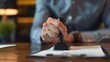 © Helois - Close-up of a hand holding a stamp over a document.