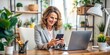 © Sirinporn - Smiling professional female worker sits at desk, checking smartphone with a bright and cheerful expression, exemplifying modern technology use in a home or office setting.