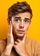© Ahmed - Portrait of a young Caucasian man who looks concerned about himself, positions of his hands are so pointing. Isolated on yellow background.