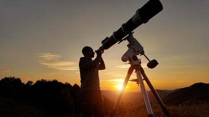 Wall Mural - Amateur astronomer looking at the evening skies, observing planets, stars, Moon and other celestial objects with a telescope just before sun down.