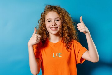 This high-resolution photograph showcases a young girl with captivating red curls, radiating happiness as she expresses a like against a vibrant blue backdrop.