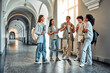 © HBS - College students stand and talk in the university building. Multiethnic young people stand near classes, diverse college friends spending time indoors after lessons.