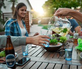 Canvas Print - Hands, people and food with lemonade water, social gathering and party with lunch. Group, outdoor and event with healthy meal, nutrition and happiness with liquid, outside and pouring with break