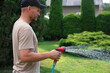 © New Africa - Man watering lawn with hose in backyard