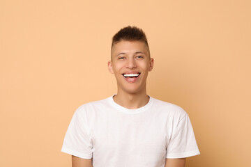 Canvas Print - Happy young man on beige background. Dental veneers