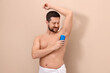 © New Africa - Man applying solid deodorant on beige background