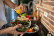 © Geber86 - Close up of woman squeezing lemon on fresh salad in a kitchen setting