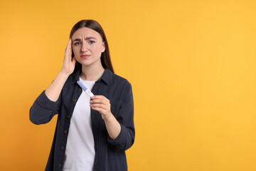 Wall Mural - Sad woman holding pregnancy test on orange background, space for text