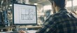 © DZMITRY - Working on architectural blueprints on a large computer screen is a man working in an office environment.