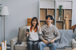 © ARMMY PICCA - Happy asian young attractive couple man and woman sit on couch use tablet shopping online furniture decorate home in the living room at new house. Young married moving home shopper online concept.