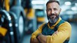 © JoxyAimages - A man with a beard and a yellow shirt, smiling confidently with his arms folded in an industrial setting. The background features yellow machinery.