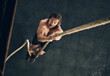 © Hira/peopleimages.com - Body, exercise and rope climbing with man in gym from above for challenge, performance or workout. Fitness, target and wellness with serious climber in health club for physical or strength training