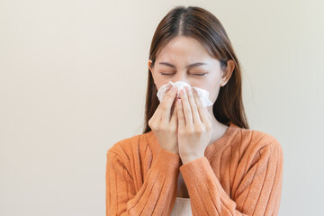 Wall Mural - Close-up woman Asian woman sneezing from allergy on tissue paper at home.