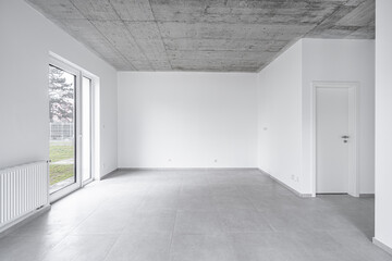 Wall Mural - Empty modern room with large glass door, concrete ceiling, and neutral tile flooring, featuring clean white walls and abundant natural light.