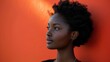 © Светлана Гуркова - A woman with curly hair gazes thoughtfully against a vibrant orange wall in natural lighting