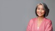 © Jean - Happy Asian Woman. Portrait of Beautiful Older Mid Aged Mature Smiling Woman in Pink Clothes Isolated on Grey Background. Anti-aging Skin Care Face Beauty Product. Banner with Copy Space.
