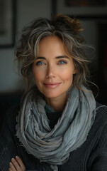 A woman with a scarf around her neck and a smile on her face. She looks happy and confident