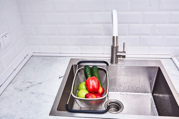 A sink with a basket of vegetables in it