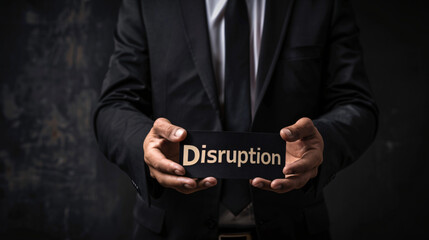 Businessman wearing black suit and tie holding a black card with the word disruption written in gold