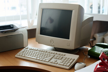 Vintage computer setup including CRT monitor, keyboard, and printer on wooden desk, creating nostalgic work environment