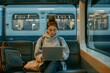 © LidiaLens - Young woman in a hoodie working on a laptop during a quiet train ride, balancing work and study while commuting