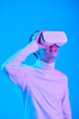 © Mediaphotos - Man wearing virtual reality headset smiling and experiencing virtual world in a blue-lit room