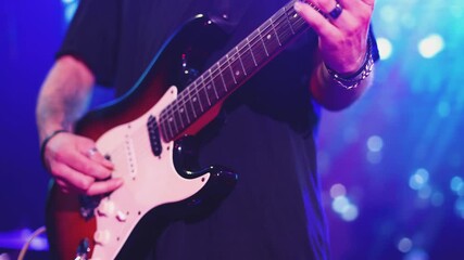 Wall Mural - Concert view of an electric guitar player with vocalist and rock band performing in club, male musician guitarist on stage with audience in a crowded concert hall arena, live music show, slow motion
