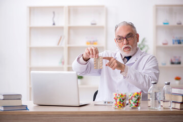 Wall Mural - Old male doctor suggesting pills in the clinic