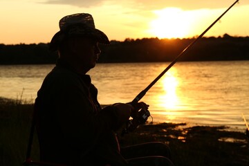 Sticker - Fisherman with rod fishing near lake at sunset