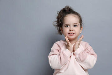 Adorable child. Portrait of smiling girl on grey background. Space for text