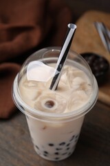 Wall Mural - Tasty milk bubble tea in plastic cup on wooden table, closeup