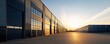 © ParinApril - Modern industrial warehouse at sunset with large windows reflecting warm colors, ideal for commercial and real estate projects.