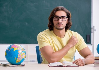 Wall Mural - Young male geography teacher in front of blackboard