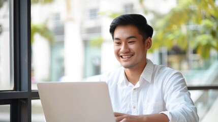 Wall Mural - Happy businessman sitting at his desk laughing while working on his laptop in the office