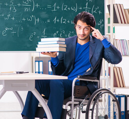 Wall Mural - Young handsome man in wheelchair in front of chalkboard