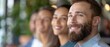 © Mikus - A man with a beard is depicted in a tight shot Three men are seen in the background A plant is placed in the foreground