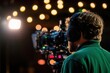 © Thanapipat - Cameraman with headset filming on set, professional video production with studio lighting in the background, creating cinematic content.
