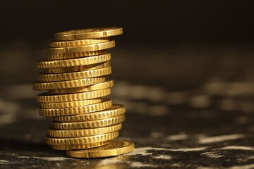 Stacked euro coins on dark table, closeup. Space for text