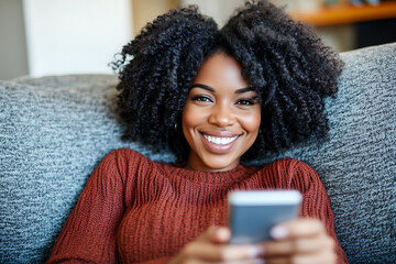 Smiling young woman relaxing on a sofa using a smartphone