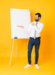 © luismolinero - Full-length shot of businessman giving a presentation on white board over isolated yellow background holding copyspace imaginary on the palm to insert an ad