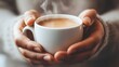 © michaswelt - A close-up of hands holding a steaming cup of coffee