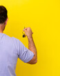 © luismolinero - Middle age man holding home keys isolated on yellow background in back position