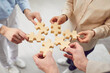 © Studio Romantic - Close up photo hands of people holding diverse pieces of wooden puzzle, team assembling jigsaw joining fragments, teamwork, search find solution, new ideas strategy development, brainstorming activity