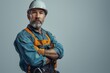 © cochisevisuals - A confident construction worker in a white hardhat and blue denim work shirt stands with his arms crossed, looking directly at the camera.